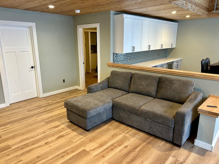 Sofa ya kulala, sofa hii inaweza kumkaribisha mgeni mmoja kwa ajili ya kulala.  Sofa hii ya kulala iko katika eneo la wazi la kuishi lenye milango ya gereji ya kioo upande wa kulia.