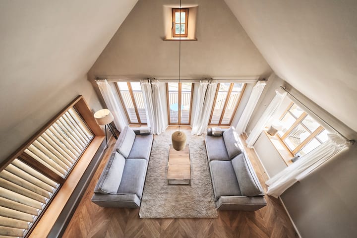 Dieses Wohnzimmer im OG ist durch die vielen Fenster sehr hell und bis in den Giebel geöffnet. Das ist der Blick vom Akovenfenster, welches sich öffnen lässt, hinunter in den Wohnbereich. z.BalkonFenster  und Zugang