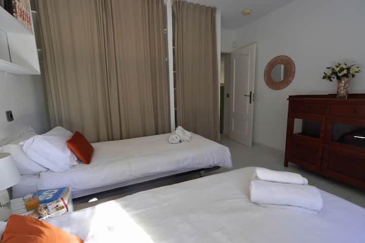 חדר השינה המרווח הזה כולל שתי מיטות נפרדות נוחות, אחסון בשפע ונוף גן מקסים - מושלם לשהייה שלווה ומאורגנת