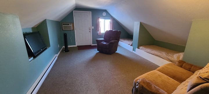 นี่คือพื้นที่ลอฟท์เหนือโรงรถพร้อมทีวีและเครื่องเล่นดีวีดีและเตียงแฝด 2 เตียง