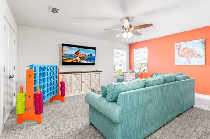 Obývacia izba na poschodí s inteligentnou televíziou a gaučom, ktorý sa dá rozložiť na posteľ