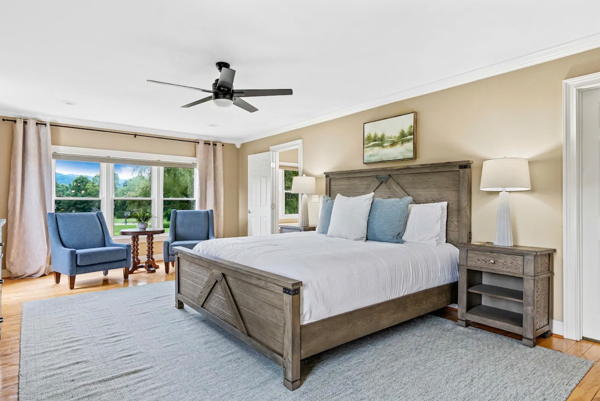 חדר שינה מואר עם פינת ישיבה מרגיעה וחלונות גדולים.