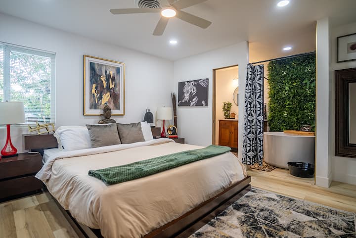 Amplio y elegante dormitorio con cama tamaño king, decoración moderna, ventilador de techo y ambiente relajante. Decorada con plantas, iluminación cálida y arte ecléctico, perfecta para noches de descanso y mañanas dignas de Instagram.