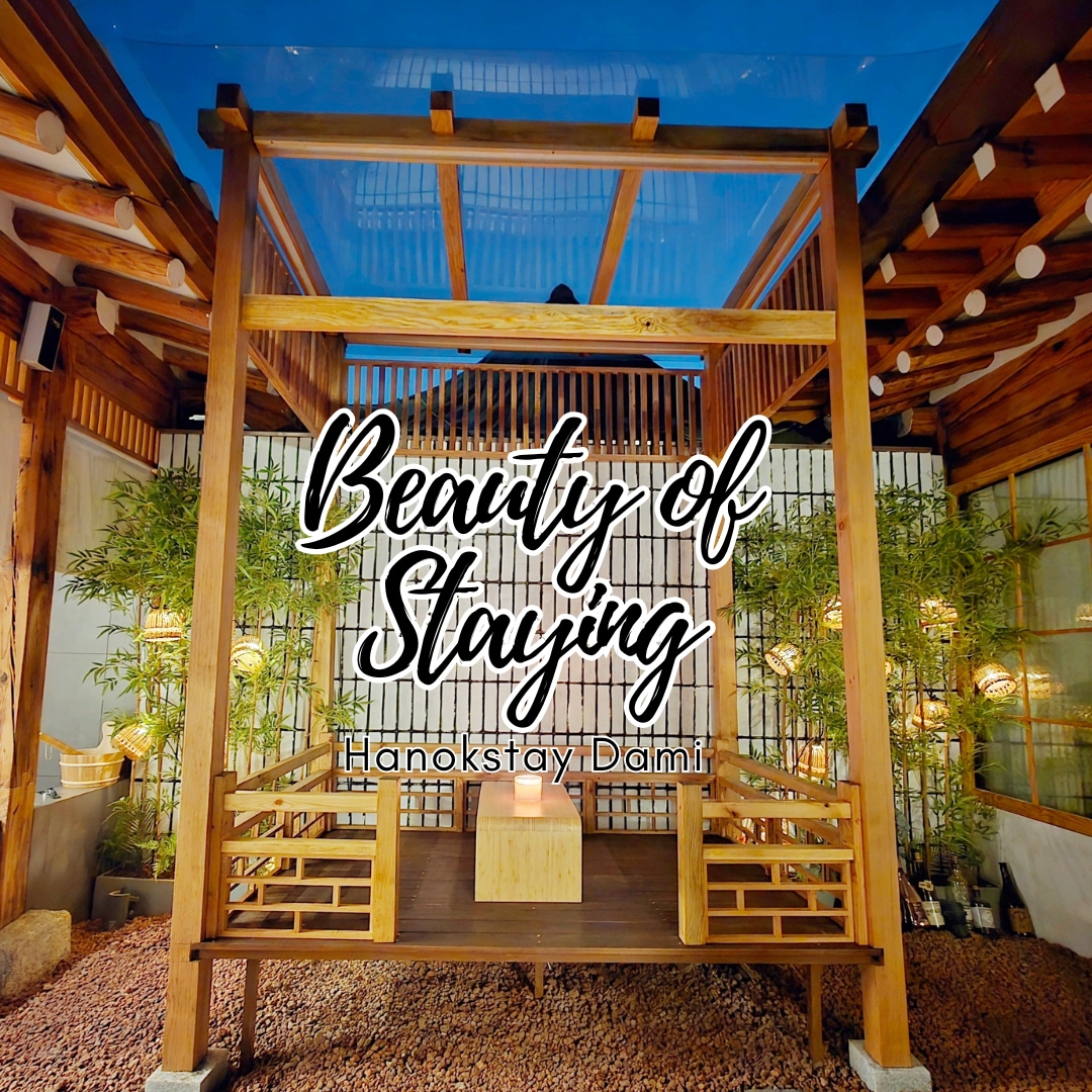 An outdoor seating area showcases a traditional structure adorned with wooden beams and a transparent blue canopy. Soft lighting highlights the surrounding bamboo foliage, creating a serene ambiance perfect for relaxation and conversation.
