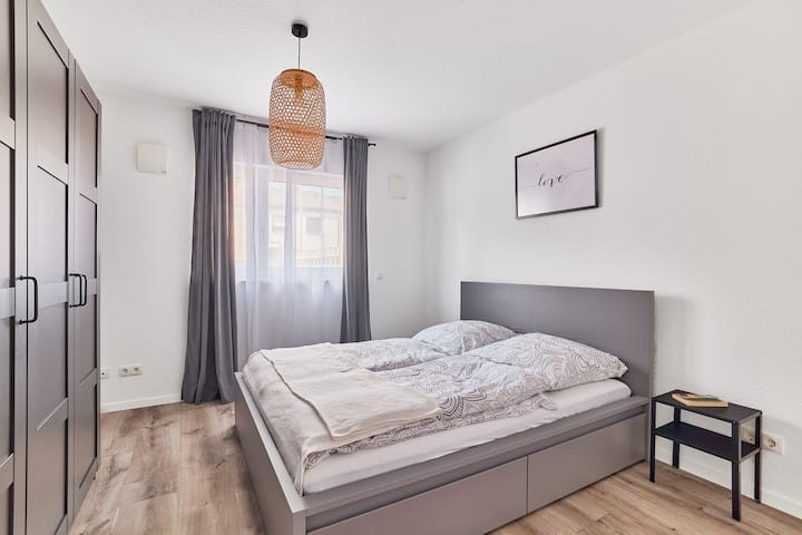 ห้องนอนที่อบอุ่นพร้อมเตียงควีนไซส์ขนาดใหญ่ ผ้าม่านสีสันสดใส และแสงสว่างทันสมัย – เหมาะสำหรับการนอนหลับที่ดี