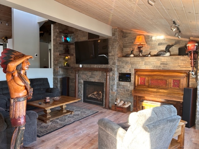 A cozy living room features a stone fireplace and elegant wooden accents. Comfortable seating arrangements surround a coffee table, while a vintage piano adds charm to the space. Soft lighting enhances the inviting atmosphere, and artwork decorates the walls.