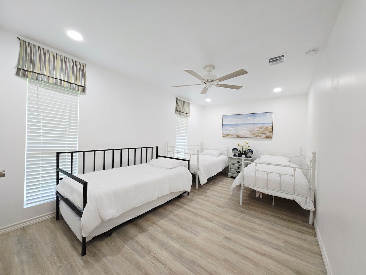 جناح بثلاثة أسرّة مثالي للأطفال والمجموعات!  تتميز بثلاثة أسرّة فردية في مساحة ساحلية مشرقة وحديثة. مع البياضات البيضاء والفن الشاطئي والكثير من المساحة، فهي الغرفة المثالية عالية السعة لقضاء عطلة عائلية!
