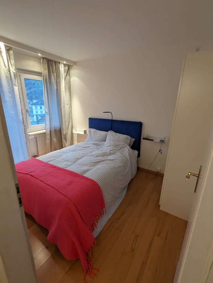 2. Camera da letto con letto matrimoniale, balcone verso il villaggio, il lago e le montagne, incluso ampio spazio di archiviazione e TV in camera.