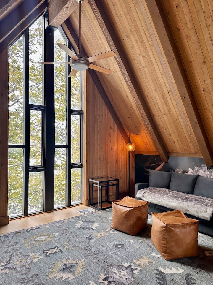 This is a cozy loft with cathedral ceiling overlooking the family room, yet private enough to turn it into a bedroom. Sofa bed quickly transforms into a comfy queen bed. Private desk. Large TV. Beautiful, tall mid-century window with stunning views.
