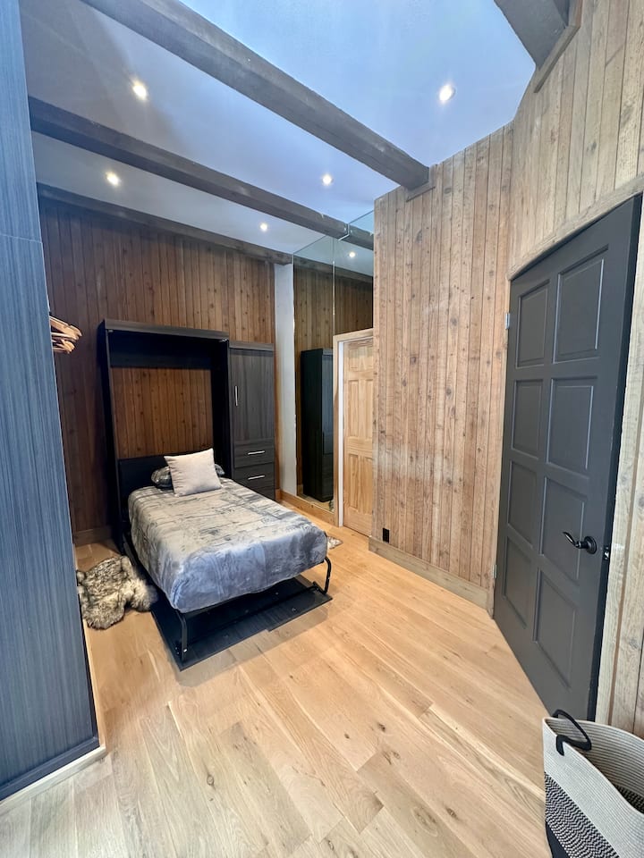 A smaller bedroom with a single bed. Very large window overlooking the Alpine forest.