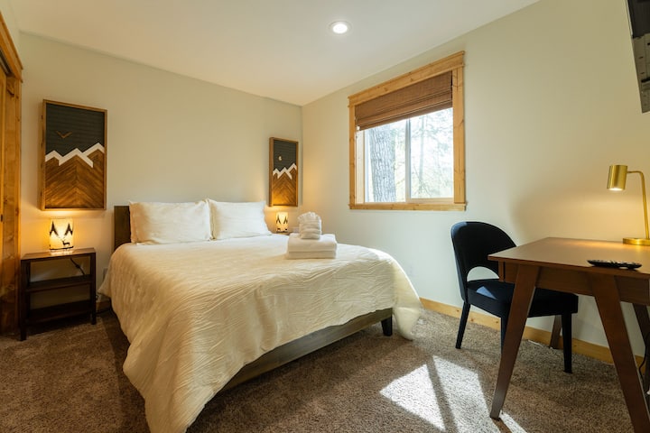 Cama queen en el dormitorio de la planta baja, con espacio de trabajo dedicado