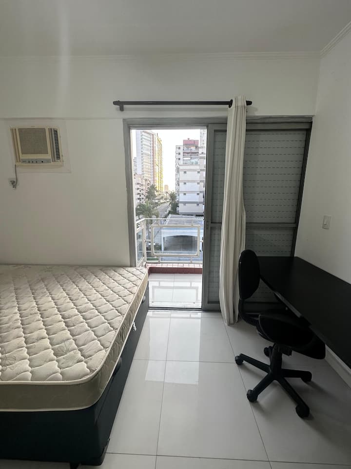 Habitación con cama de matrimonio, mesa y silla para trabajar con balcón y vistas a la calle