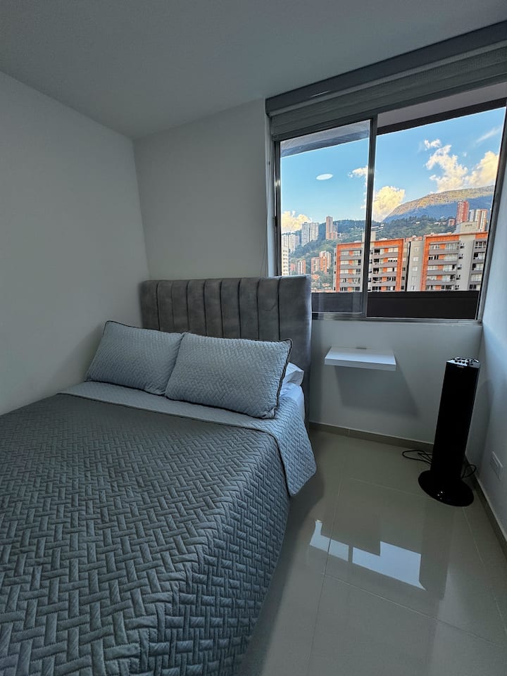 Habitación 2, tiene vista a la ciudad y montañas de Medellín, cuenta con cama doble, 4 almohadas, persiana y closet.
