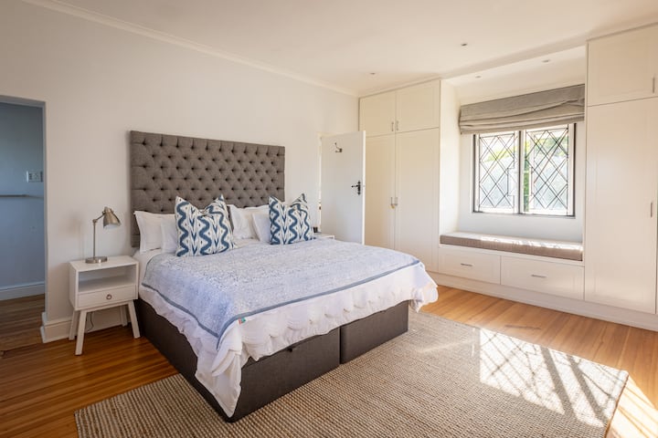 غرفة نوم رئيسية واسعة مع سرير بمقاس كبير وخزانة ملابس ودش داخلي ومرحاض. 