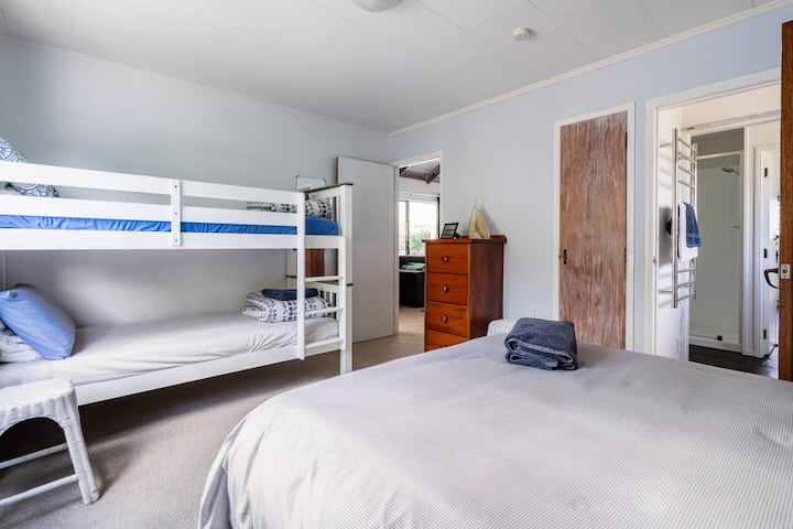 Dormitorio 2 con cómoda cama tamaño queen y literas con buenos colchones cómodos. Las fotos tomadas con mi teléfono muestran un niño alto y un pequeño armario colgante.  La puerta está abierta al inodoro a la derecha con vista al baño.
