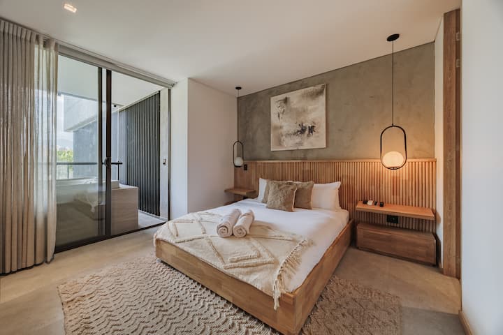 Disfruta de una espaciosa habitación con una cama tamaño queen, baño privado en suite, TV de 65 pulgadas, aire acondicionado y acceso directo a un balcón privado con jacuzzi para la máxima comodidad y relajación.