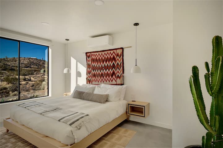 King bed with an organic Avocado mattress, custom white oak nightstands, MushLume pendants, and an original Navajo rug