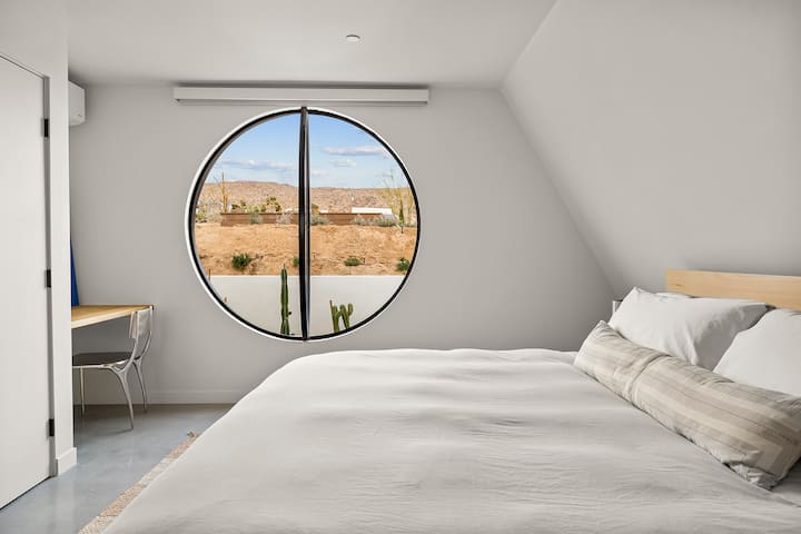 Downstairs bedroom includes a built-in desk and a 5’ operable circular pivot window
