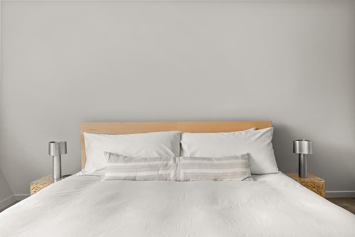 Downstairs bedroom with a king bed, organic Avocado mattress, and custom made hay nightstands