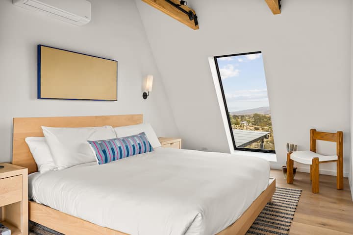 Upstairs en suite bedroom with king bed, organic Avocado mattress, and sculptural Human Home sconces