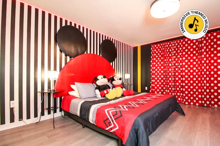 Per i fan Disney di tutte le età, questa camera da letto a tema Topolino porta gioia in ogni soggiorno! Dotata di letto king-size con testiera giocosa, tende a pois, illuminazione perimetrale a LED, scrivania, TV a parete, ventilatore a soffitto e arredi incantevoli per un comfort magico.