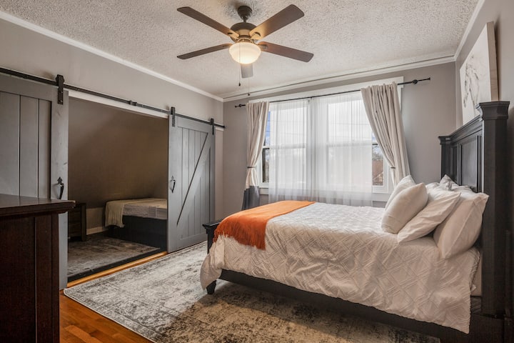 غرفة النوم 1 في المنزل مع سرير كبير وسريرين مزدوجين خلف الأبواب الخاصة وتلفزيون وخزانة ملابس وخزانة ملابس.