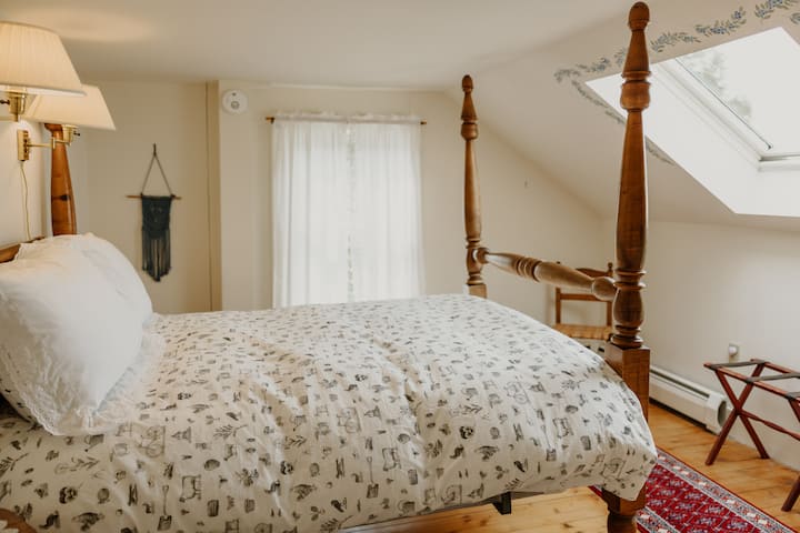 The "Sunshine" bedroom on the 2nd floor with a full-sized bed, bedside tables and lamps, luggage racks, spacious closet with hangers, and a fun skylight overlooking the surrounding hayfields and the covered bridge!