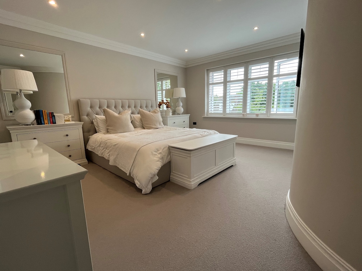 جناح رئيسي واسع مع سرير بمقاس سوبر كينج وخزانة ملابس وحمام داخلي كبير مع حمام مستقل ودش كبير ومغسلة مزدوجة ومرحاض.