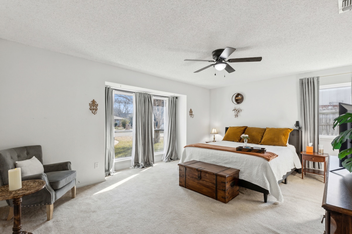 The master bedroom is comfy with a big Cal king bed with cotton sateen sheets, blackout curtains, 2 nightstands, side table lamp, reading lamp, ceiling fan, full-size dresser, walk-in closet, chair, and side table.