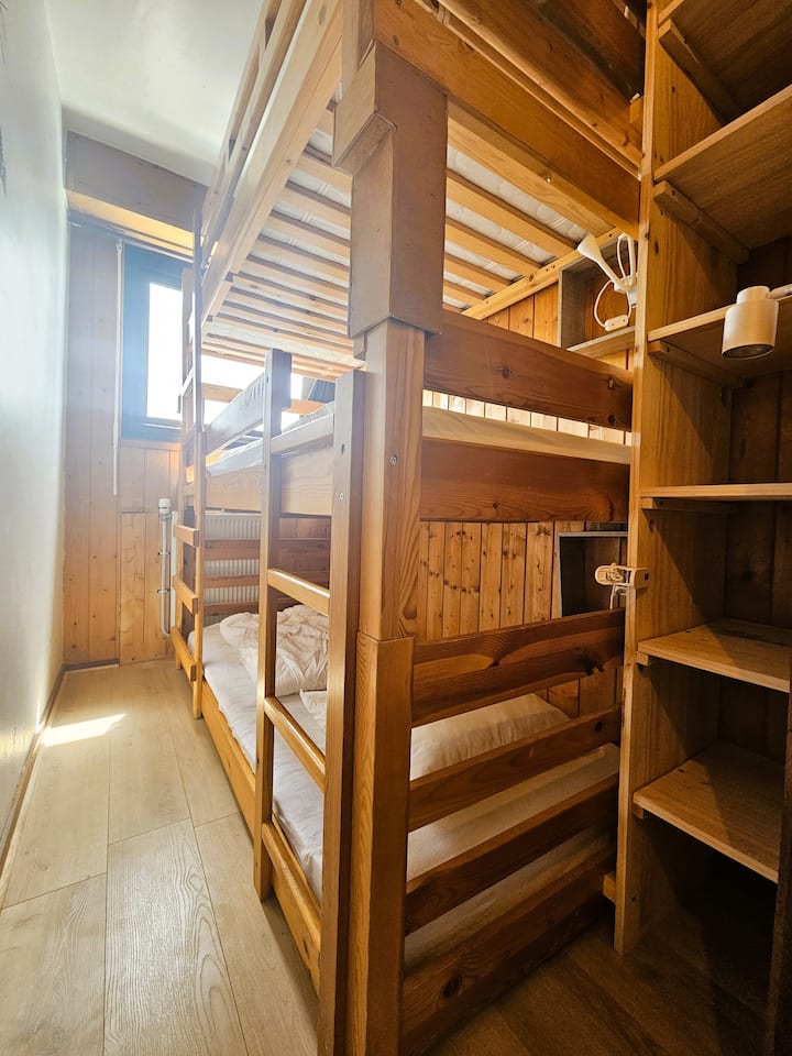 Chumba hiki cha mtindo wa nyumba ya mbao kilicho na dirisha kina kitanda cha ghorofa tatu (vitanda 3 vya sentimita 90)