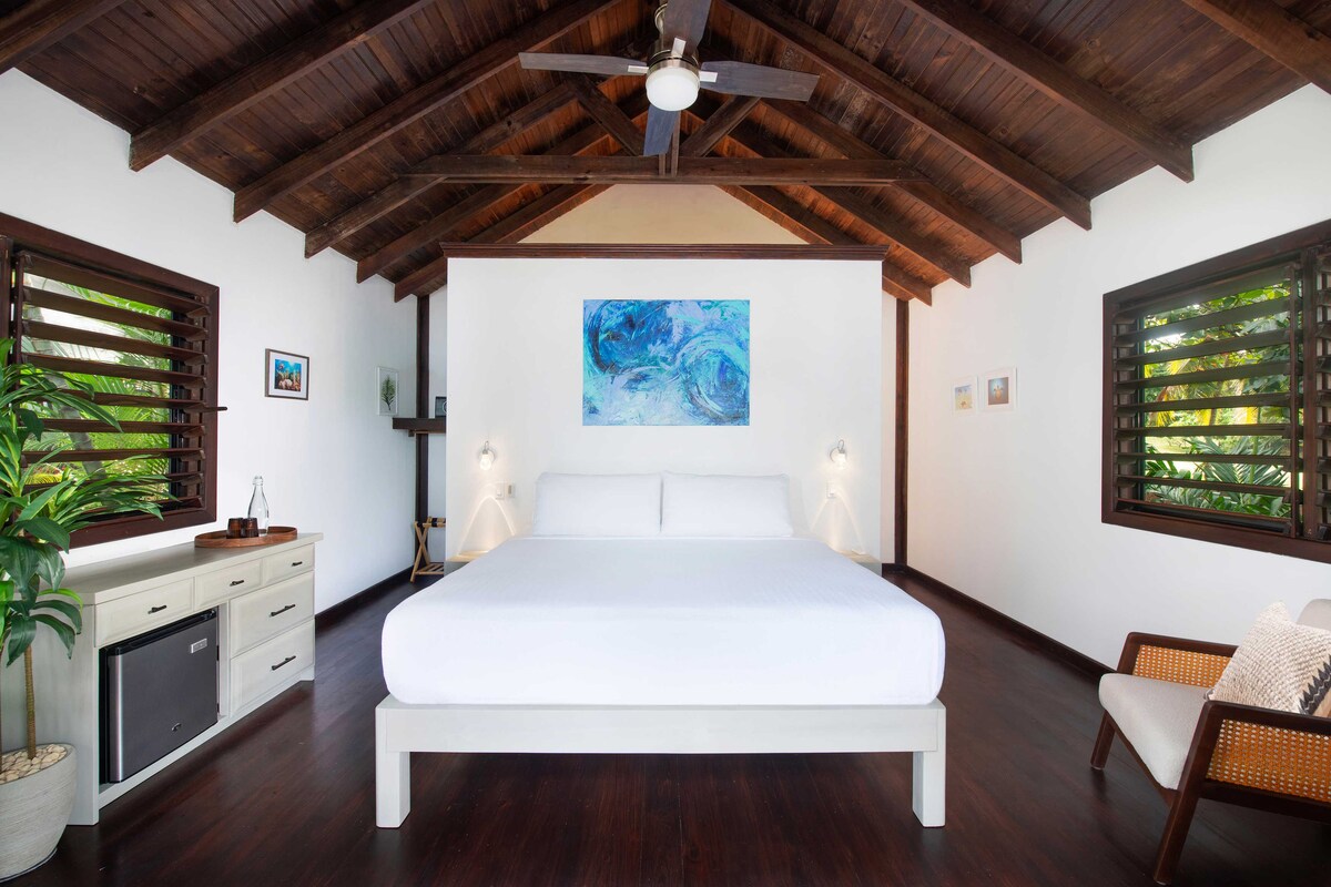 A king bed awaits at your private beachfront accommodation with Puerta Azul. The room also features a minifridge, dresser for storage, keypad safe, and ensuite bathroom.