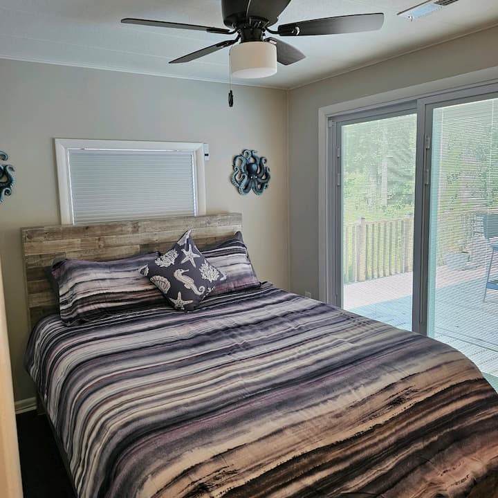 Bedroom 2 features a large screen HDTV, electric fireplace (for ambiance or heat), whole house sound, ceiling fan, and sliders with a view of the pool area. Built-in blinds can be closed for privacy.