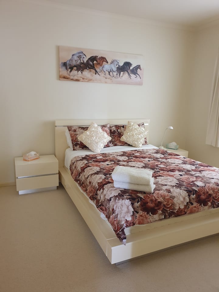 This bedroom comes with a queen-sized bed, a pair of bedside draws, floor to ceiling four door built in robes, and a side window with venetian blind and a blockout curtain. 