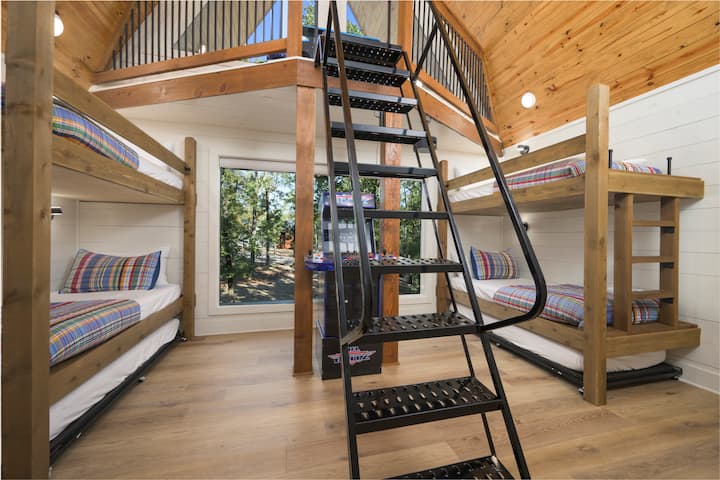 Cozy bunk room with loft and scenic forest window view.