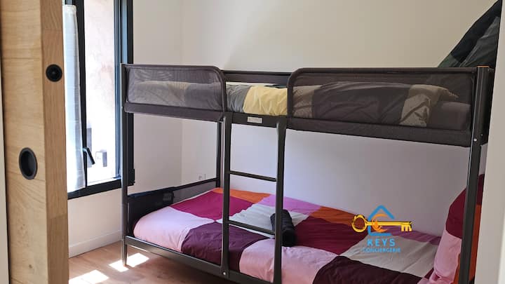 ห้องพักสว่างสดใสมีเตียงสองชั้นสีสันสดใสเหมาะสำหรับคืนที่สะดวกสบาย หน้าต่างมีวิวที่น่ารื่นรมย์และการระบายอากาศที่ดีเหมาะสำหรับครอบครัวที่มีเด็ก