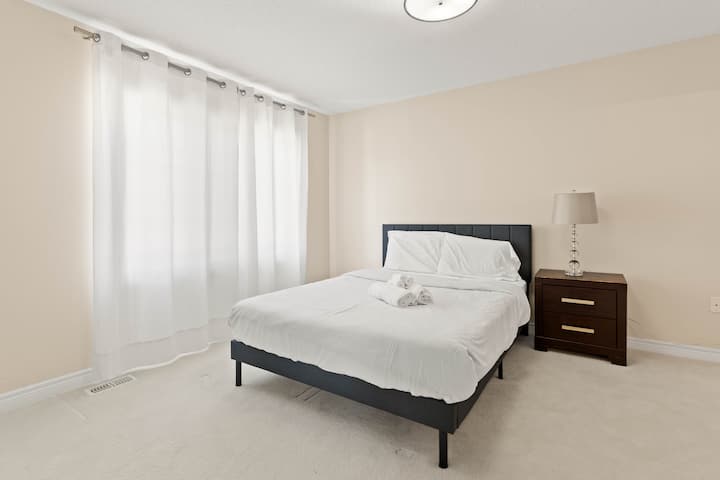 Una habitación acogedora con una cama cómoda, cortinas blancas y una mesita de noche con una lámpara. Perfecto para una noche de sueño relajante.




