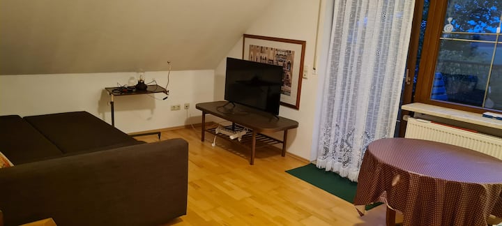 Sovrum med soffa och smart TV tillgång till balkong med utsikt över trädgården