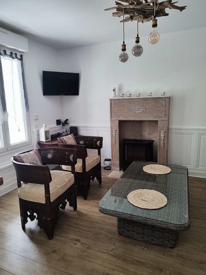 Una acogedora sala de estar con un sofá convertible, televisión, zona de comedor y chimenea falsa equipada con un radiador eléctrico que imita las llamas de una chimenea.