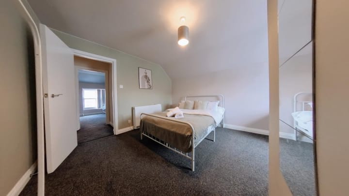 חדר שינה עם מיטה זוגית: בחדר השינה הזה יש מיטה זוגית עם מצעים נקיים ועיצוב פשוט. הגוונים הנייטרליים והעיצוב המינימליסטי יוצרים סביבה נינוחה, אידיאלית לשינה לילית נוחה.
