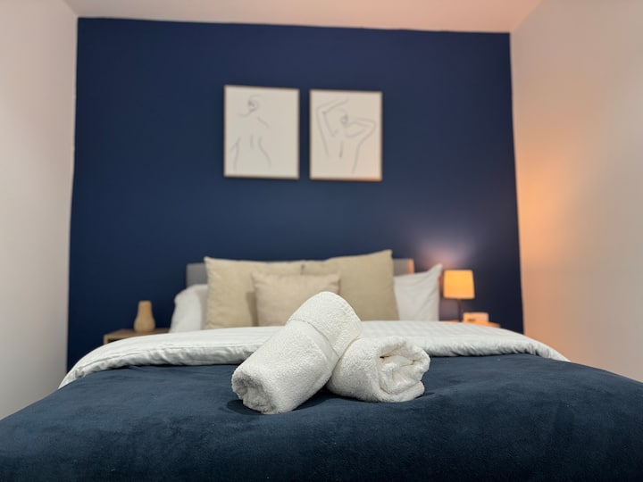 Udobna i elegantna: ova spavaća soba s upečatljivim plavim ukrasnim zidom nudi savršen spoj udobnosti i stila. Plišani krevet odjeven je u mekanu posteljinu, što ga čini privlačnim utočištem za miran san.