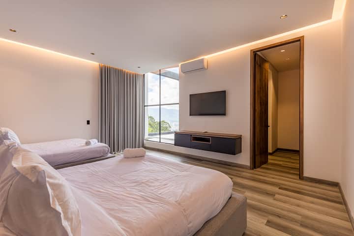 Amplio y elegante, este dormitorio ofrece dos lujosas camas tamaño queen, un televisor inteligente y una luz impresionante desde grandes ventanas, perfecto para estancias de amigos o familiares.

