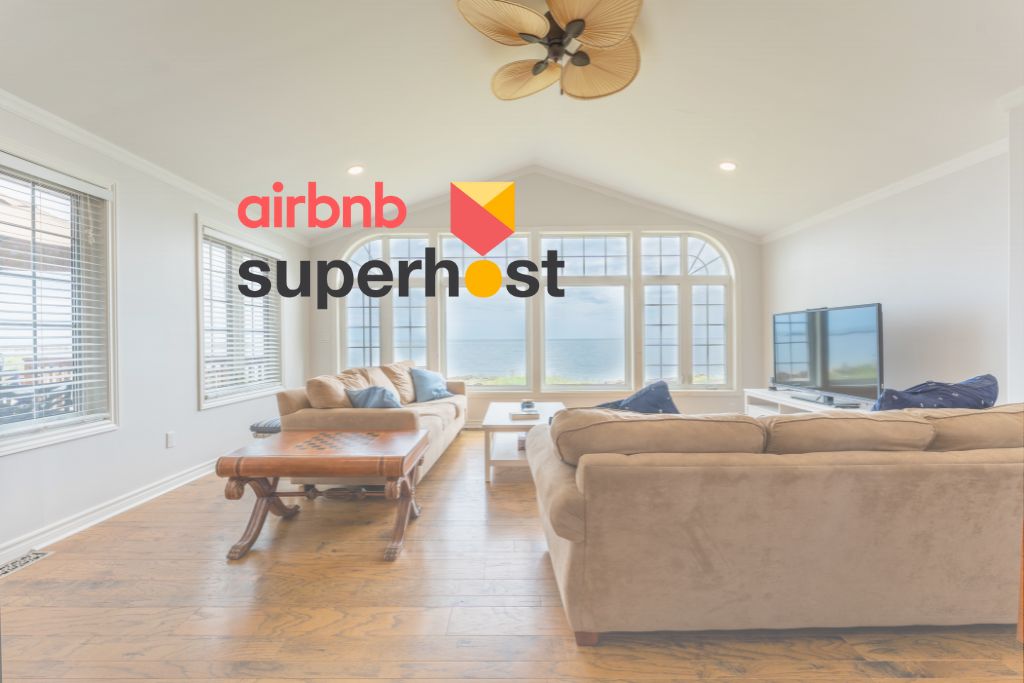 A spacious living area features large windows offering expansive views of the lake. Comfortable seating arrangements are visible, complemented by a wooden coffee table. A TV is positioned against the wall, and light wood flooring enhances the airy atmosphere.