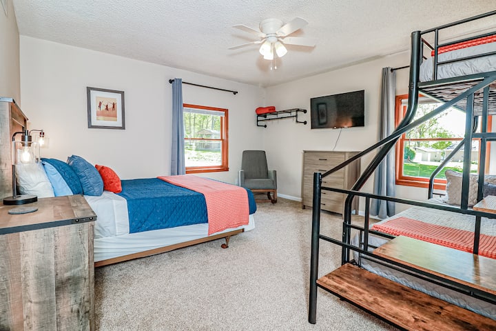 Queen bed + twin over full bunk bed. Twin floor mattress available on request (room sleeps max 5). There's a dresser, clothing rack, ceiling fan, rocking chair, and TV. Windows have light filtering mini blinds and room darkening curtains.