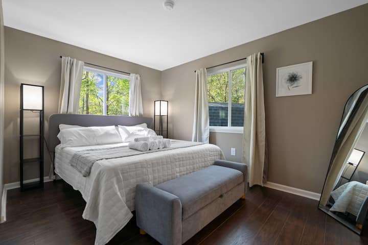 Dormitorio 1 de la cabaña "azul": el dormitorio principal ofrece una cama tamaño king de lujo, mesitas de noche con lámparas y un armario de tamaño completo. 