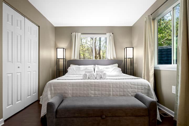 La chambre principale dispose d'un lit king size de luxe, de tables de nuit avec lampes et d'un placard grand format. 