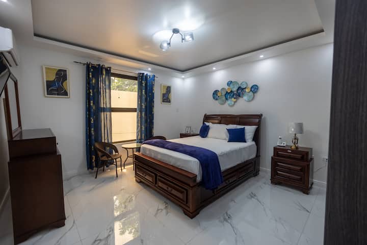 Chambre secondaire avec un lit queen size confortable, des accents bleu vif et une décoration minimaliste, créant un espace chaleureux et accueillant.