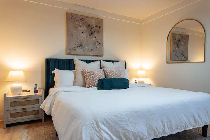 After a long day of travel enjoy this king bed and blackout curtains! Plush duvet bedding, soft and firm pillows, a sound machine, alarm clock, USB-C + A chargers, a ceiling fan, and Fiji water, all just for you.