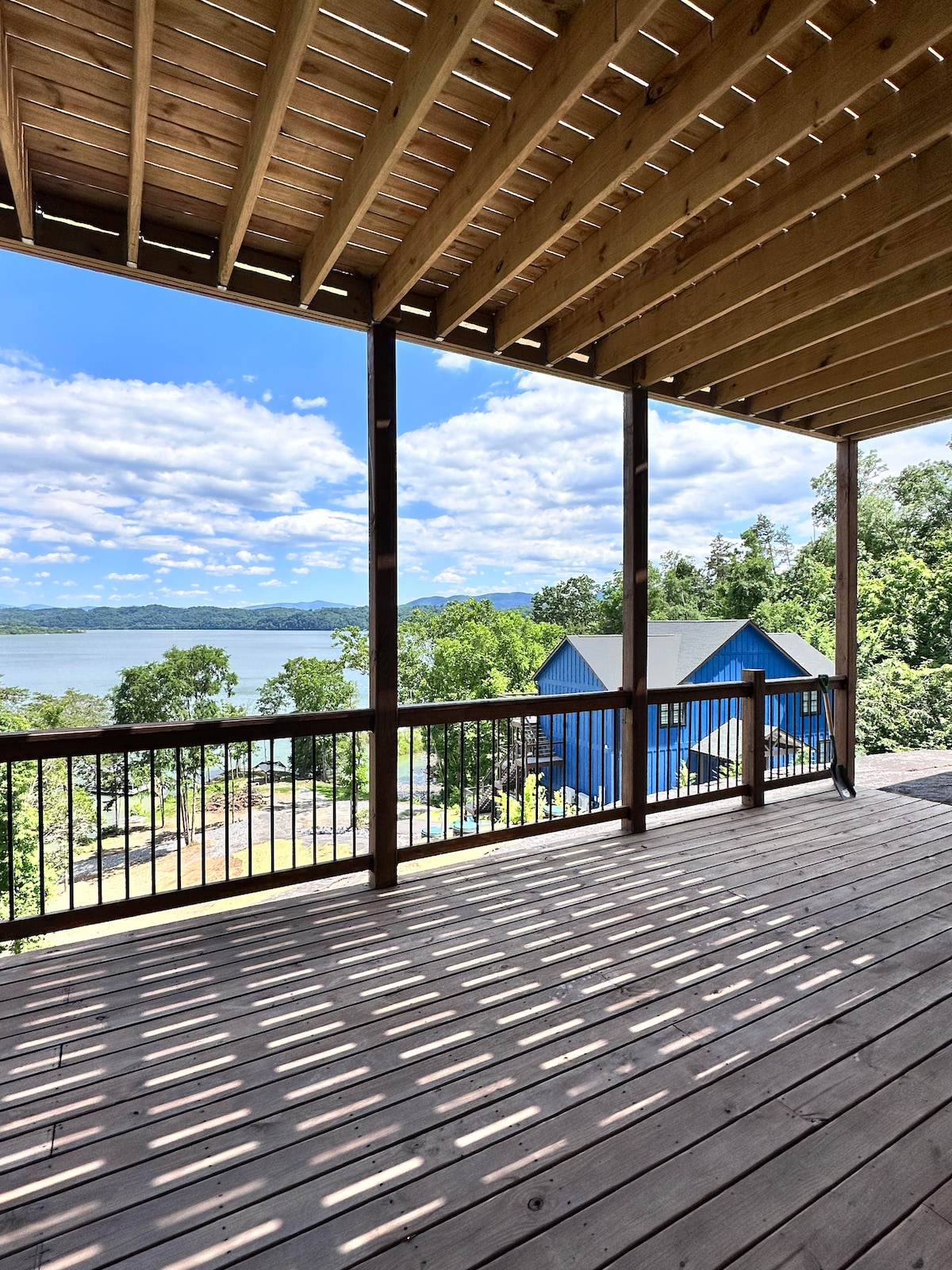 An expansive wooden deck offers unobstructed views of Douglas Lake and the surrounding landscape. The open space features sturdy railings and ample room for outdoor seating, inviting guests to enjoy the natural beauty and fresh air.