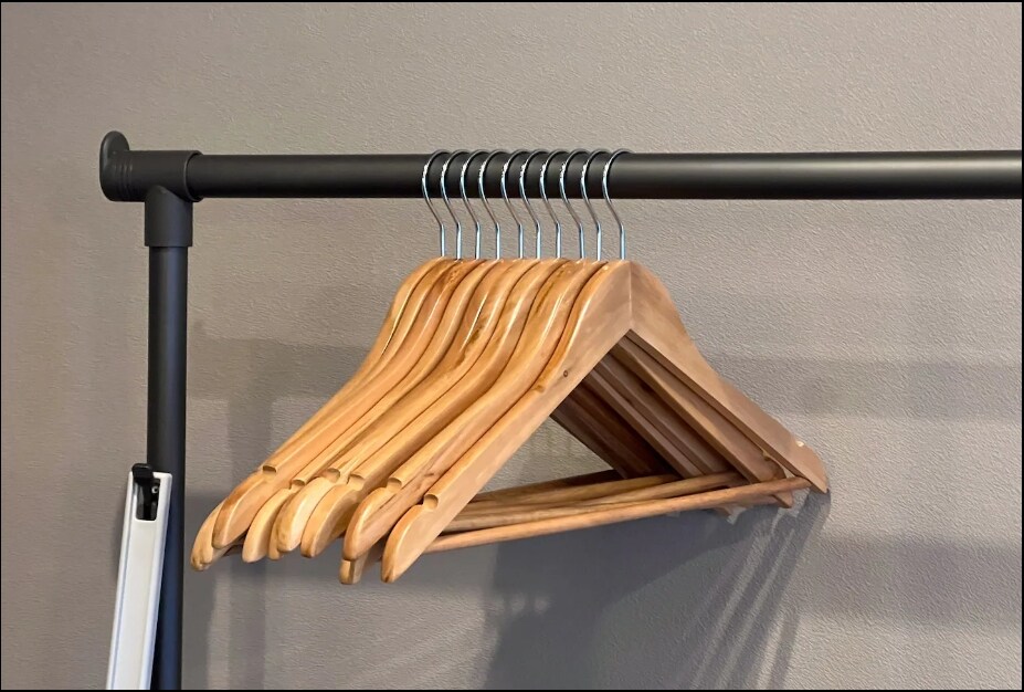 A simple wooden hanger rack is shown, displaying several wooden hangers in a row. The hangers are arranged neatly, with a focus on their natural wood finish and minimalist design.