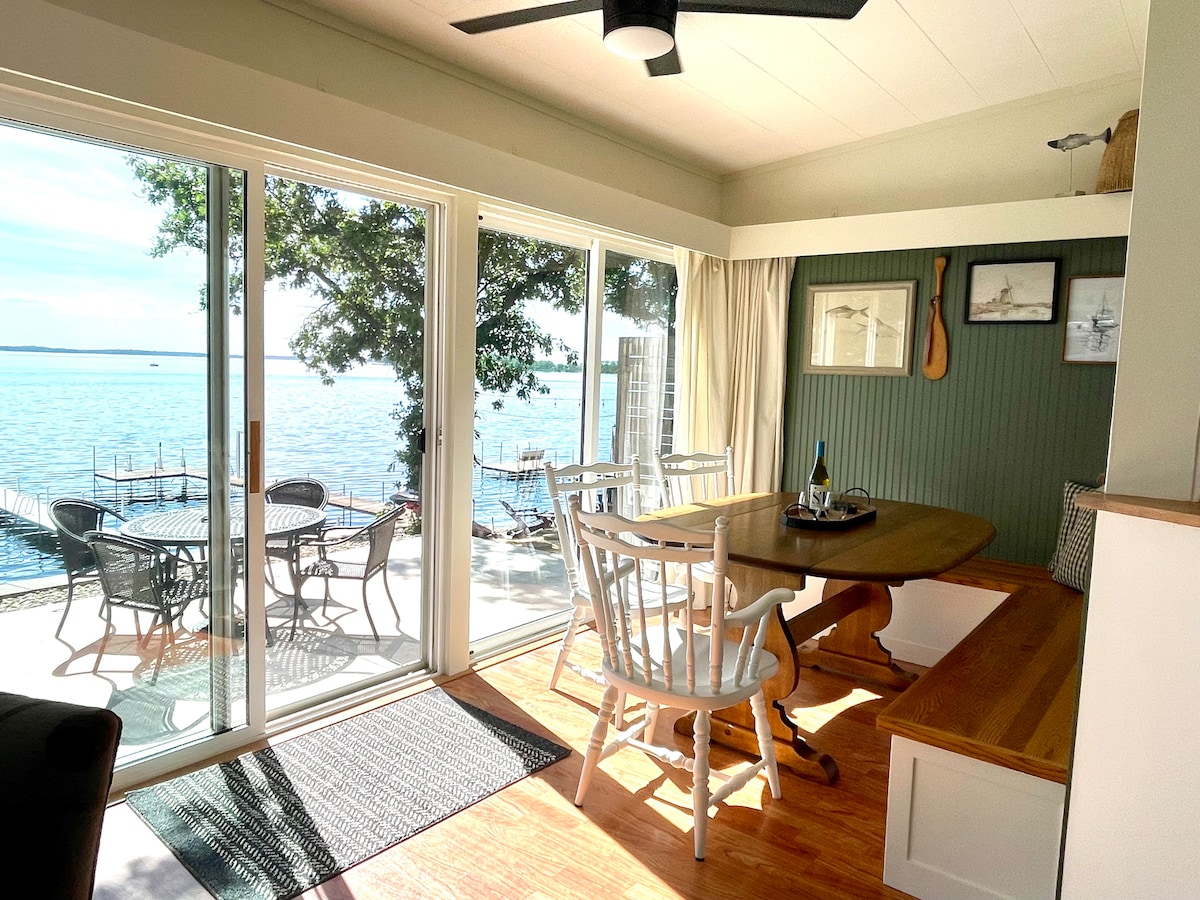 A bright dining area features a wooden table surrounded by chairs and a built-in bench. Large sliding doors offer a view of Spirit Lake, enhancing the connection between the interior and the natural surroundings.